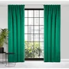 A pair of dark green curtains hangs on either side of a large window with a grid pattern. A potted plant is visible to the left, and two small black tables are in the foreground. Produktbild-Vorschau