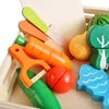 A close-up view of a wooden toy set featuring various fruits and vegetables, along with a toy fish and peeler, arranged in a wooden crate. Náhled obrázku produktu