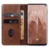 A brown leather flip phone case is open, showing credit cards and a banknote inside, with a smartphone displaying the time and date on its screen. Produktbild-Vorschau