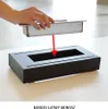 A hand is shown inserting a metal burner into a black fireplace base. Náhľad obrázku produktu