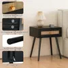 A black nightstand with a rattan drawer front is shown in a bedroom setting, next to a bed. The image also includes close-up shots of the product's features. Podgląd zdjęcia produktu