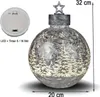 A decorative Christmas bauble with a winter forest scene and LED lights, shown with its battery compartment. Produktbild-Vorschau
