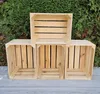 Four wooden crates are arranged on a gray surface in front of a green hedge. Produktbild-Vorschau