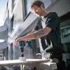 A man is using a Bosch drill to make a hole in a piece of wood. Voir les images du produit