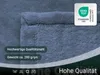 A close-up of a blue plush blanket with text overlays and a certification logo. Produktbild-Vorschau