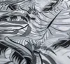 A close-up view of a fabric with a tropical leaf pattern in shades of gray and white. Produktbild-Vorschau