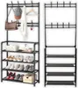 Two black metal hall trees with shoe shelves are shown side-by-side against a white background. The left hall tree is accessorized with a hat, bag, scarf, and shoes, while the right hall tree is empty. Produktbild-Vorschau
