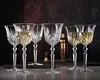 A group of crystal wine glasses filled with white wine, set on a dark surface with a blurred background. Anteprima dell’immagine prodotto