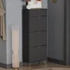 A tall, dark gray shoe cabinet with three flip-down drawers stands in a room next to a floor lamp and a coat rack. Podgląd zdjęcia produktu