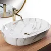 A marble-patterned sink with a gold faucet is shown on a wooden countertop, with a round mirror in the background. Anteprima dell’immagine prodotto