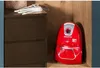 A red vacuum cleaner is stored in a wooden niche next to a dark brown dresser with hangers on top. Anteprima dell’immagine prodotto
