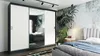 A bedroom scene featuring a large sliding door wardrobe with mirrored doors, a bed with a plush headboard, and a tropical-themed wallpaper. Produktbild-Vorschau
