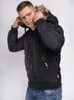 A man wearing a black hooded winter jacket and blue jeans, posing against a white background. Náhled obrázku produktu