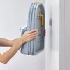 A person is holding a folded ironing board against a white wall. Náhľad obrázku produktu