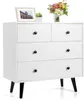 A white dresser with black legs and black knobs, decorated with a framed picture and a bouquet of flowers. Náhled obrázku produktu