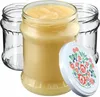 A glass jar filled with a yellow substance, with two empty glass jars behind it, and a decorative lid in the foreground. Produktbild-Vorschau