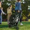 A family walks through a park, with one person carrying a portable grill. Produktbild-Vorschau