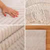 A collage of four images showing different close-up views of a beige rug with a striped pattern, including a hand touching the rug and the rug rolled up. Podgląd zdjęcia produktu