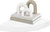 Decorative bookends with arched shapes on top of books, placed on a white shelf. Voir les images du produit