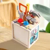 A wooden toy tool chest with various tools and accessories on top, placed on a wooden surface. Produktbild-Vorschau