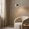 A floor lamp is placed next to a chair in a room. Produktbild-Vorschau