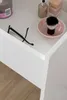 A close-up view of a white vanity table with makeup and accessories. Produktbild-Vorschau