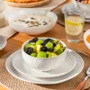 A table setting with a fruit salad in a bowl, soup in another bowl, and a glass of water with lemon. Náhled obrázku produktu