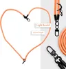 A product image showing an orange lanyard with black clasps, arranged in a heart shape, with additional product shots and text overlays. Produktbild-Vorschau