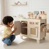 A young child is playing with a wooden toy kitchen. Anteprima dell’immagine prodotto