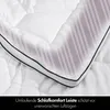 A close-up of a white comforter with a decorative striped pattern and a black and gray trim. Produktbild-Vorschau
