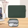 A dark green laptop sleeve and a small pouch containing a white mouse and charging cable are displayed on a wooden desk, next to a laptop and a vase of dried flowers. Anteprima dell’immagine prodotto