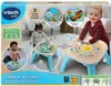 A Vtech Baby activity table with children playing with it, presented on product packaging. Produktbild-Vorschau