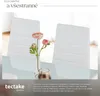 A marketing image featuring two white chairs and flowers on a table, with text overlays. Náhled obrázku produktu