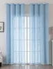 Two light blue sheer curtains are hanging in front of a window.