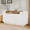 A modern white and black sideboard with LED lighting, displayed in a well-lit room with decorative items on top. Produktbild-Vorschau