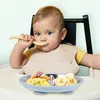 A baby is sitting in a high chair and eating from a divided plate. Produktbild-Vorschau