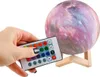 A hand is holding a remote control in front of a galaxy-themed moon lamp. Náhľad obrázku produktu