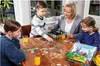 A family playing a board game at a wooden table. Voir les images du produit