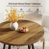 A round wooden table with a vase of yellow flowers and a plate of croissants. Produktbild-Vorschau