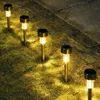 Solar garden lights illuminating a grassy path next to a stone walkway. Anteprima dell’immagine prodotto