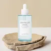 A bottle of Skin1004 Madagascar Centella Hyalu-Cica First Ampoule is displayed on a stone pedestal against a light beige and white background. Voir les images du produit