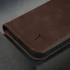 Close-up of a dark brown leather iPhone case with a cutout logo. Produktbild-Vorschau