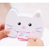A close-up shot of a white cat-shaped toy camera with two small cards being inserted into it. Produktbild-Vorschau