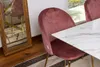 A close-up of a pink velvet dining chair next to a marble-look table, with a vintage mirror in the background. Anteprima dell’immagine prodotto