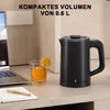 A black electric kettle is shown on a desk next to a glass of orange juice and a laptop. Produktbild-Vorschau
