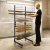 A man is placing a shelf onto a drying rack in what appears to be a workshop or manufacturing facility. Voir les images du produit