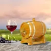 A wooden barrel with a tap, a glass of red wine, and a bunch of grapes are displayed on a stone surface with a vineyard in the background. Náhled obrázku produktu