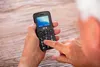 An older person's hands are holding a black SPC Fortune 2 4G senior mobile phone, with their finger pressing a button on the keypad. Anteprima dell’immagine prodotto