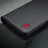 A close-up view of a black leather phone case with red stitching and a red bull logo. Anteprima dell’immagine prodotto