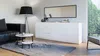 A modern living room with a black leather sofa, a white credenza, and a floor lamp. Náhľad obrázku produktu